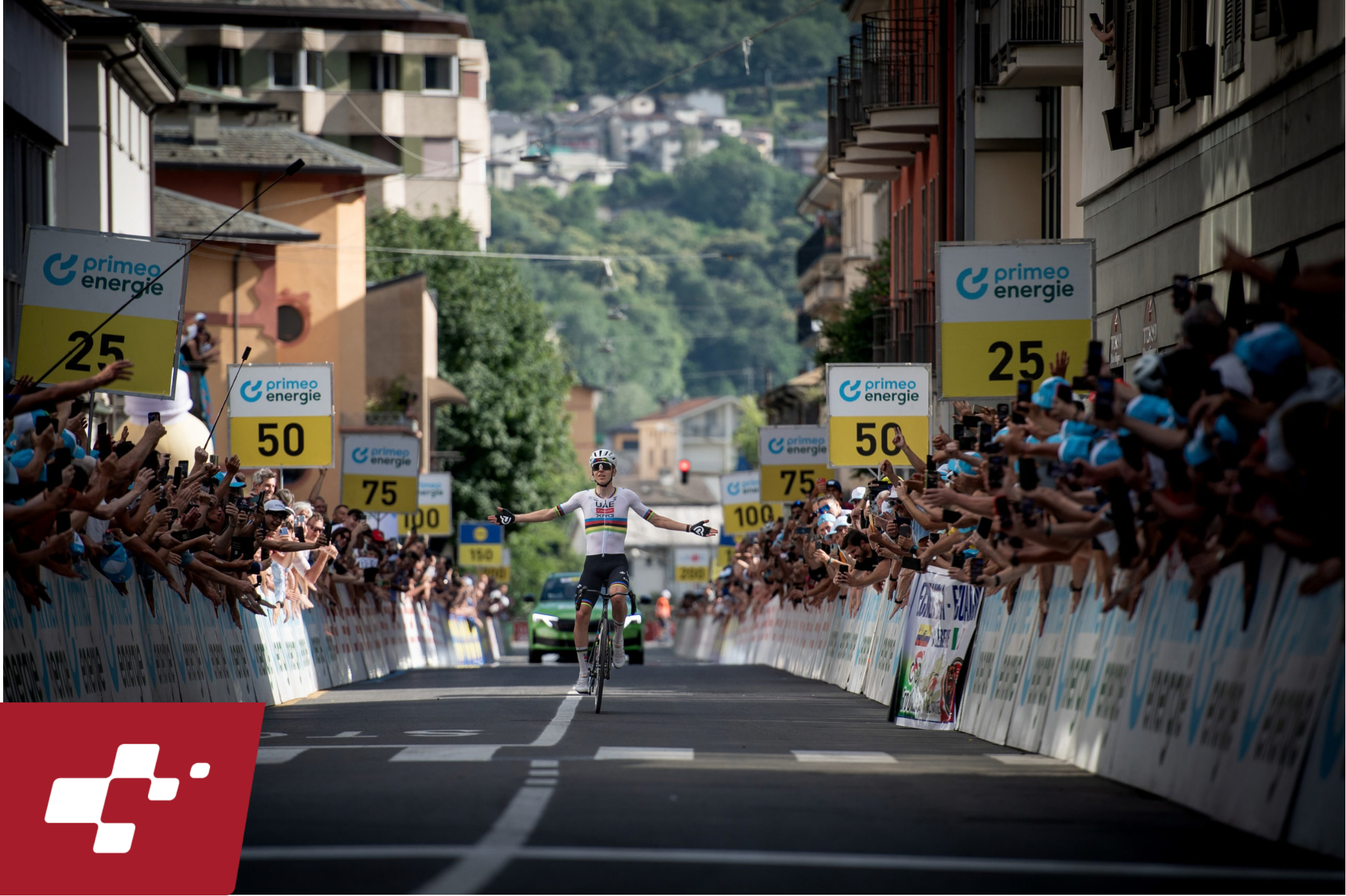 Tour de Suisse rider celebrates at the finish line as fans and sponsor boards line the race-day route.